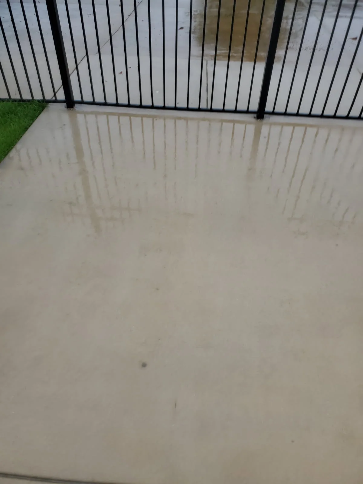 The same concrete beside a black gate after washing