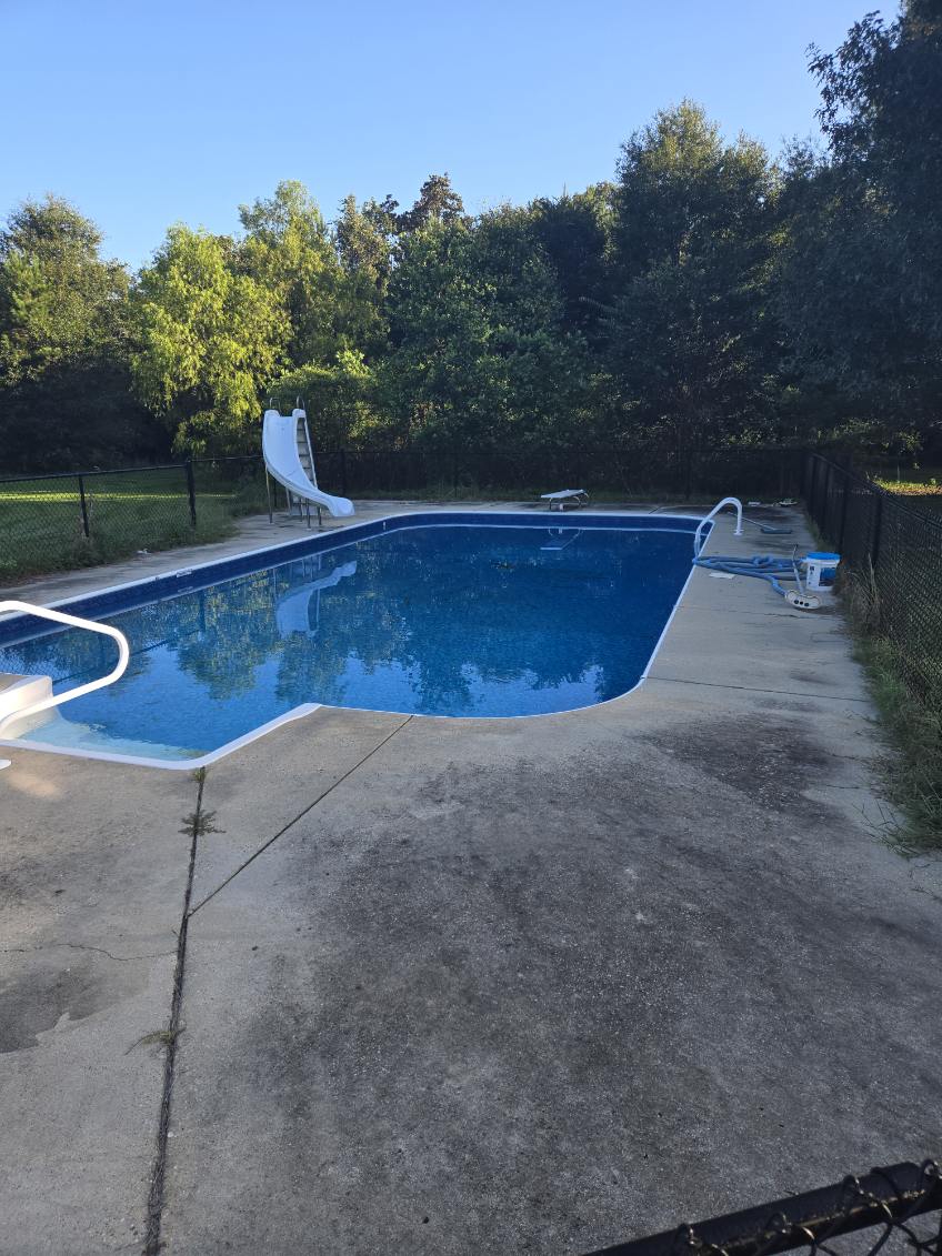 Dark buildup on concrete around a swimming pool before washing