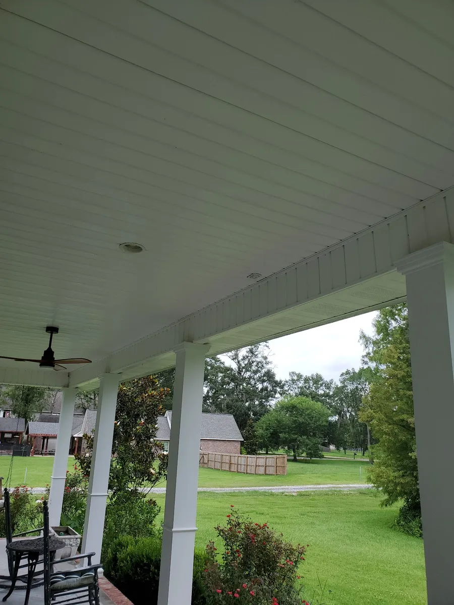 A covered porch with ceiling fans and rocking chairs, cleaned
